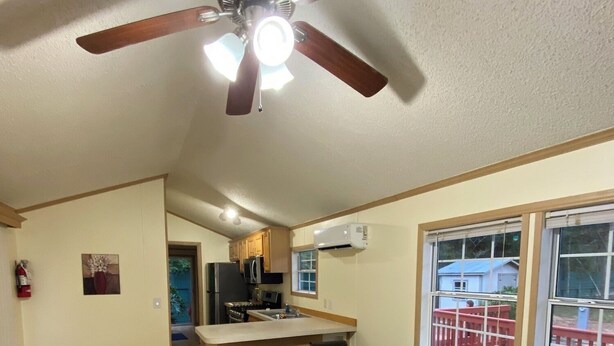 Ein geräumiger Wohnbereich mit Deckenventilator, eine Küche mit Bar und ein großes Fenster mit Blick.