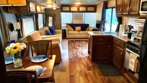 A compact RV interior with a dining area, kitchenette, and seating space.