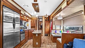 Cocina compacta para autocaravana con armarios de madera, electrodomésticos de acero inoxidable y una pequeña isla.