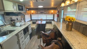 A compact kitchen with a central island, built-in microwave, and a dining area with leather stools.