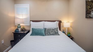 A neatly made bed with two pillows, a bedside table with a lamp, and a wall-mounted picture. - Charming 1-Bedroom with AC, private yard, & full kitchen (Yuma)
