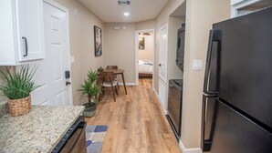 A kitchen with a refrigerator, wooden flooring, and a dining area with chairs and a table. - Charming 1-Bedroom with AC, private yard, & full kitchen (Yuma)