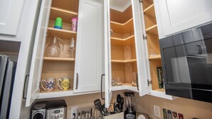 A kitchen with open cabinets revealing utensils, a coffee maker, and a blender. - Charming 1-Bedroom with AC, private yard, & full kitchen (Yuma)