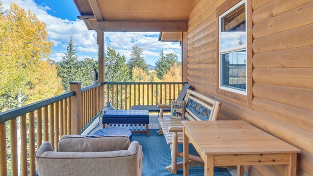 Eine Holzterrasse mit einer Bank, einem Tisch und Stühlen.