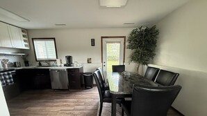 Una cocina moderna con comedor, piso de madera y una planta grande en maceta.