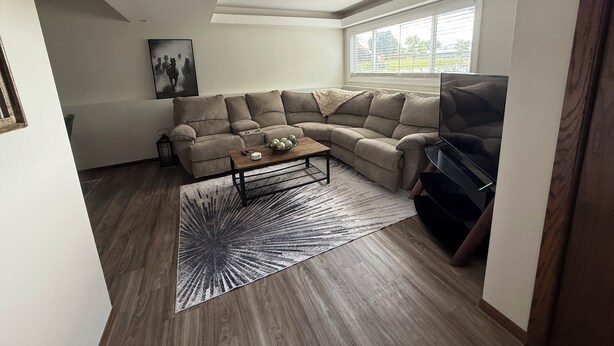 Una sala de estar con un sofá modular, una mesa de centro, una alfombra y un televisor.