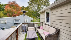 A deck with a wicker sofa, a table, and a lantern. - Stay & Play in Plymouth: Spacious Home w/ Yard (Plymouth)