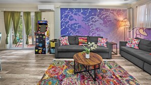A living room with a gray sofa set, colorful pillows, a multicolored rug, a wooden coffee table, and a wall with a purple abstract design. - Modern & Bright Escape: Mins Beach, Pool, Hot Tub! (Sarasota)