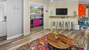 A modern living room with a wooden coffee table, colorful rug, and a TV mounted on the wall. - Modern & Bright Escape: Mins Beach, Pool, Hot Tub! (Sarasota)