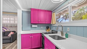 A compact kitchen with pink cabinets, a dishwasher, and a sink. - Modern & Bright Escape: Mins Beach, Pool, Hot Tub! (Sarasota)