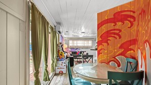 A dining area with a glass table and teal chairs, a colorful mural on the wall, and a view of the living room in the background. - Modern & Bright Escape: Mins Beach, Pool, Hot Tub! (Sarasota)