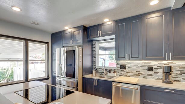 A modern kitchen with dark cabinets, stainless steel appliances, and a large island. - Great Outdoor Space! Family Home in SLC Suburbs (Midvale)