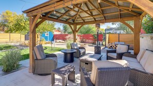 A covered outdoor patio with wicker furniture, a fire pit, and a pergola structure. - Great Outdoor Space! Family Home in SLC Suburbs (Midvale)