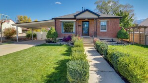 A single-story brick house with a covered front porch, a front door, and a small front yard with well-maintained grass and shrubs. - Great Outdoor Space! Family Home in SLC Suburbs (Midvale)