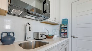Een moderne keuken met een roestvrijstalen spoelbak, een broodrooster, een waterkoker en een magnetron.