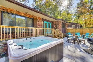 A hot tub in a backyard with a wooden deck, a blue door, and a wooden fence.