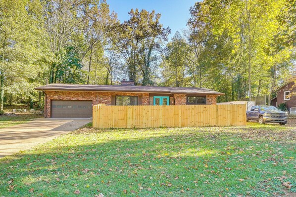 A single-story brick house with a garage, a wooden fence, and a driveway.