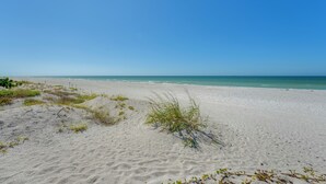 Una playa arenosa con cielo azul despejado y océano.