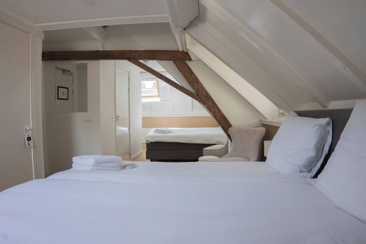 A bedroom with a bed, a chair, and a wooden beam structure.
