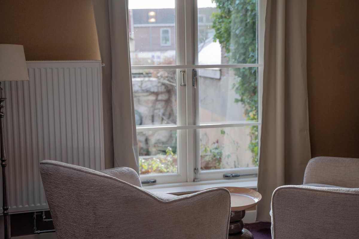 A room with two chairs, a table, and a window with a view of buildings and greenery outside.