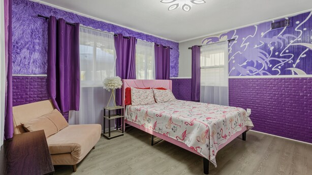 A bedroom with a bed, a chair, a nightstand, and a wall with a floral pattern. - Trendy & Relaxing: Close to Beach ~ Pool ~ Hot Tub (Sarasota)