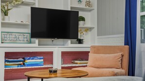 A living room with a flat-screen TV mounted on the wall, a sofa, a coffee table, and shelves with decorative items. - Trendy & Relaxing: Close to Beach ~ Pool ~ Hot Tub (Sarasota)