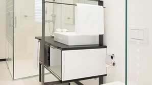 A modern bathroom with a glass-enclosed shower, a white sink, and a toilet.