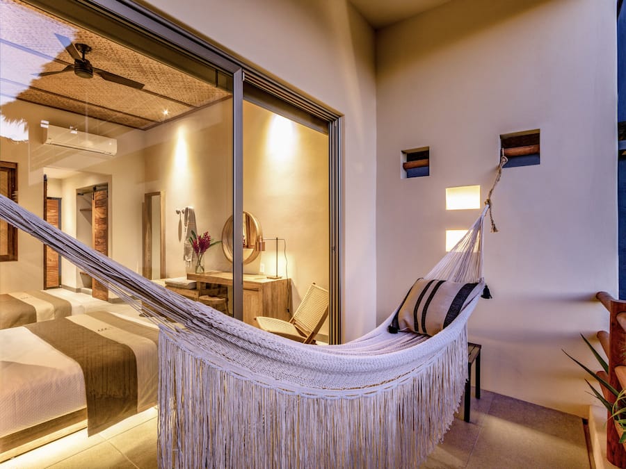 Una hamaca en una habitación con una cama, una silla y una mesita.