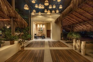 A spacious indoor area with a wooden floor, potted plants, and a reception desk. - Casa Bocana Huatulco (Santa María Huatulco)
