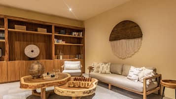 A cozy living room with a wooden bookshelf, a round coffee table, a sofa, and a decorative wall piece.
