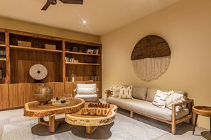 A cozy living room with a wooden bookshelf, a round coffee table, a sofa, and a decorative wall piece. - Casa Bocana Huatulco (Santa María Huatulco)
