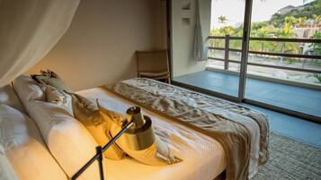 A bedroom with a large bed, a nightstand, and a view of a balcony with a railing.