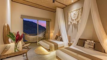 A bedroom with two beds, a large window, a hammock, and a view of the hills.