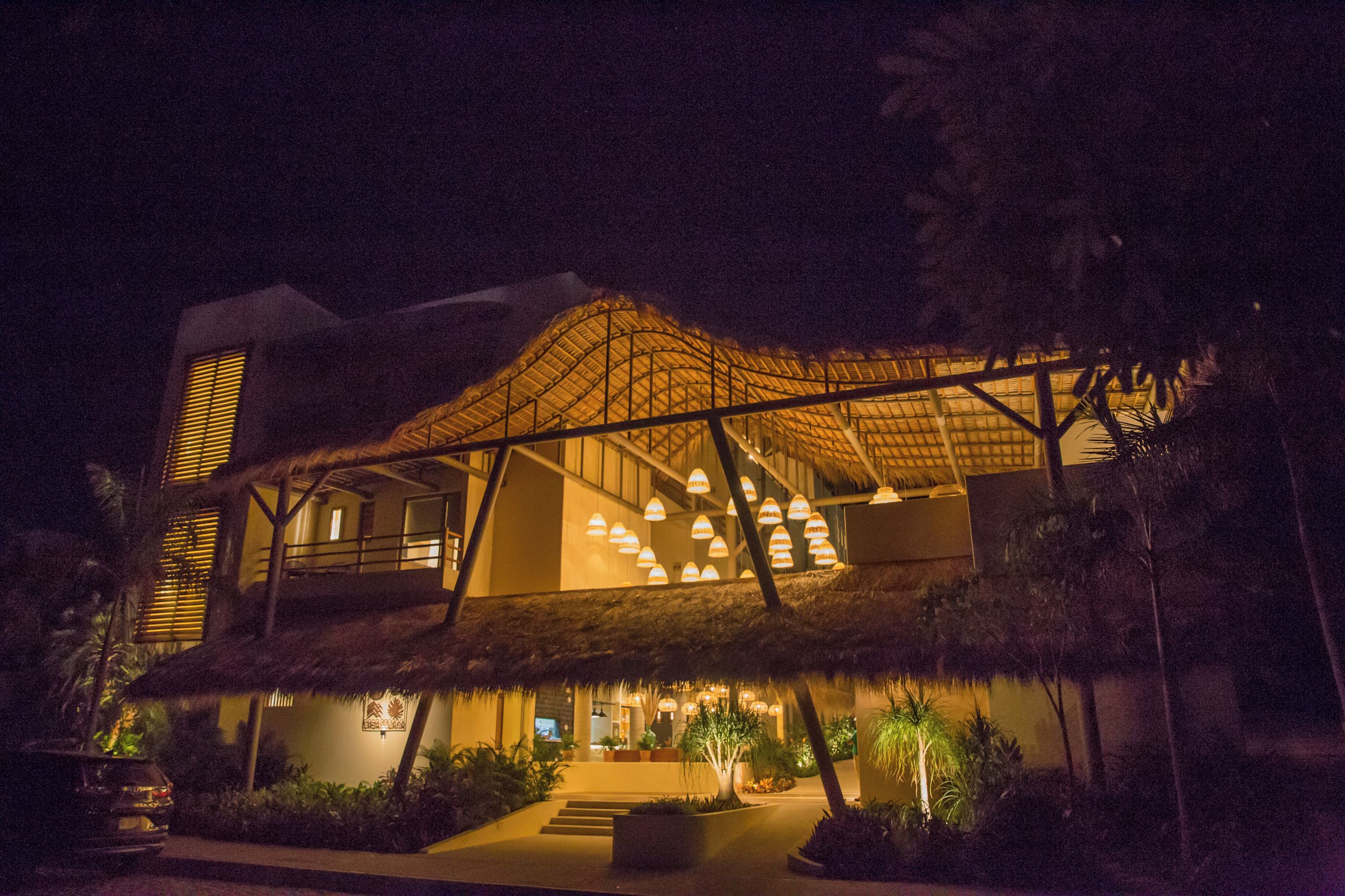 Un edificio moderno con una estructura de techo singular e iluminación cálida.
