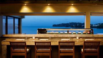 Un bar con vista al mar, equipado con una parrilla y taburetes de bar.