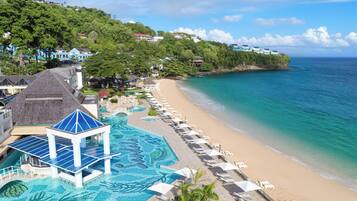 Un resort en la playa con piscina, sombrillas y vistas al océano.