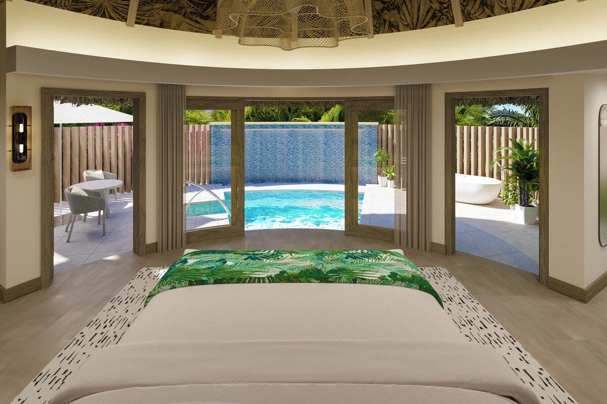 Une chambre dotée d’un grand lit, offrant une vue sur une piscine, et comprenant un patio aménagé avec du mobilier d’extérieur.