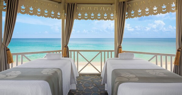 Una camera con due letti, vista sull'oceano e un balcone con ringhiera.