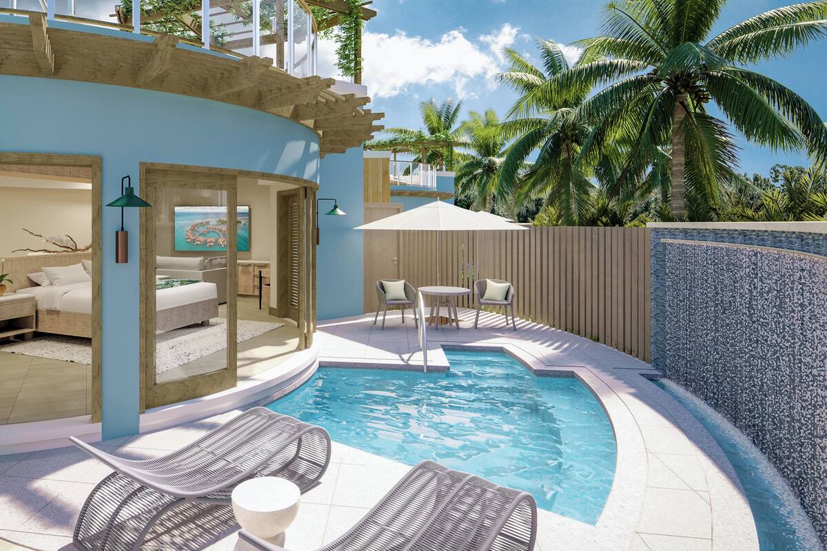 A pool area with lounge chairs, a small table, and a view of the ocean.