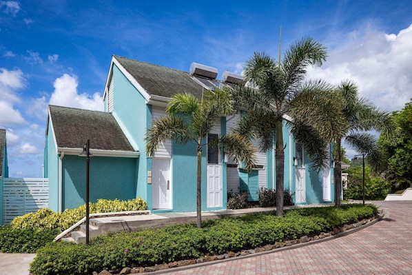 A two-story building with a teal exterior, white doors, and a small front porch. - Sandals Regency La Toc (Castries)