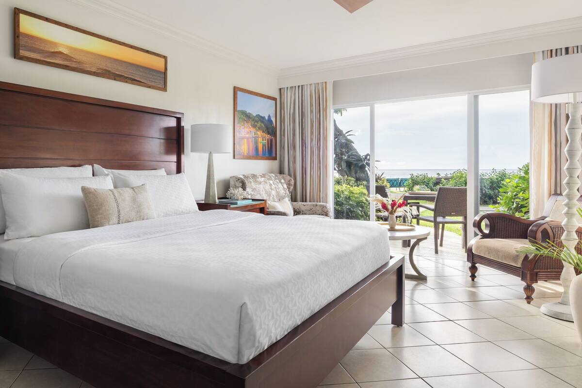 A spacious bedroom with a large bed, a wooden headboard, and a view of the outdoors through a sliding glass door.