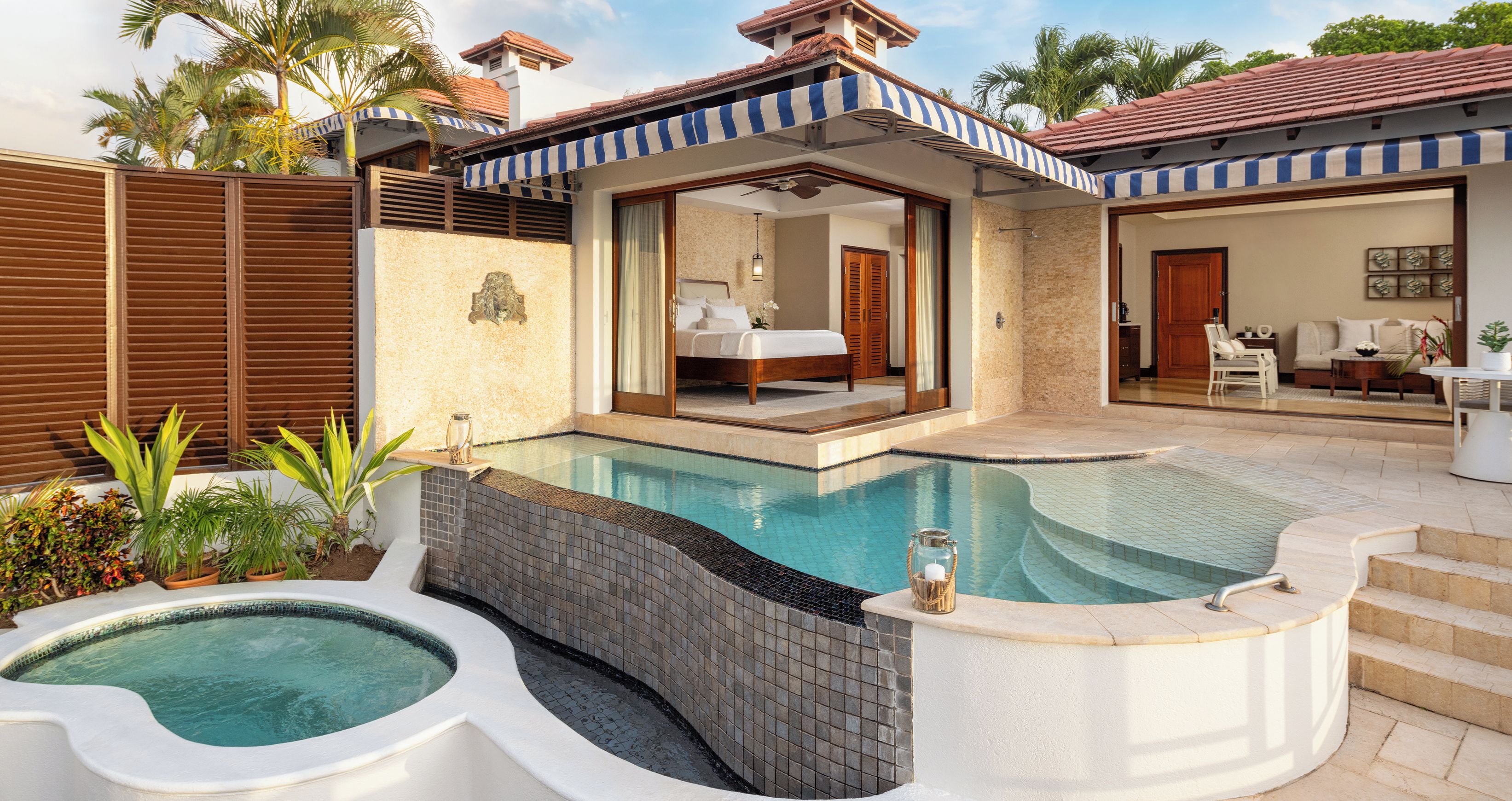 A swimming pool with a hot tub, a bedroom, and a sitting area with a view of the pool.