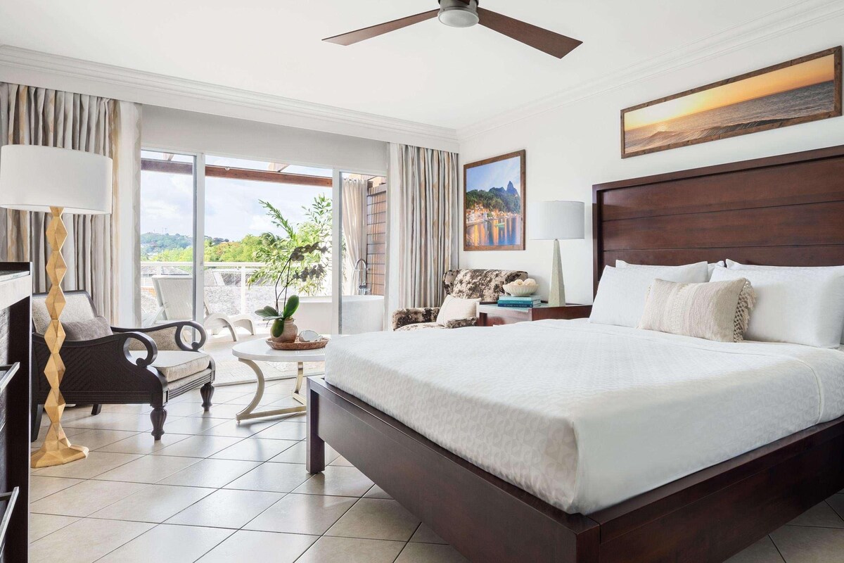 Une chambre d’hôtel spacieuse, dotée d’un grand lit, d’un balcon avec vue, d’un bureau et d’une chaise.