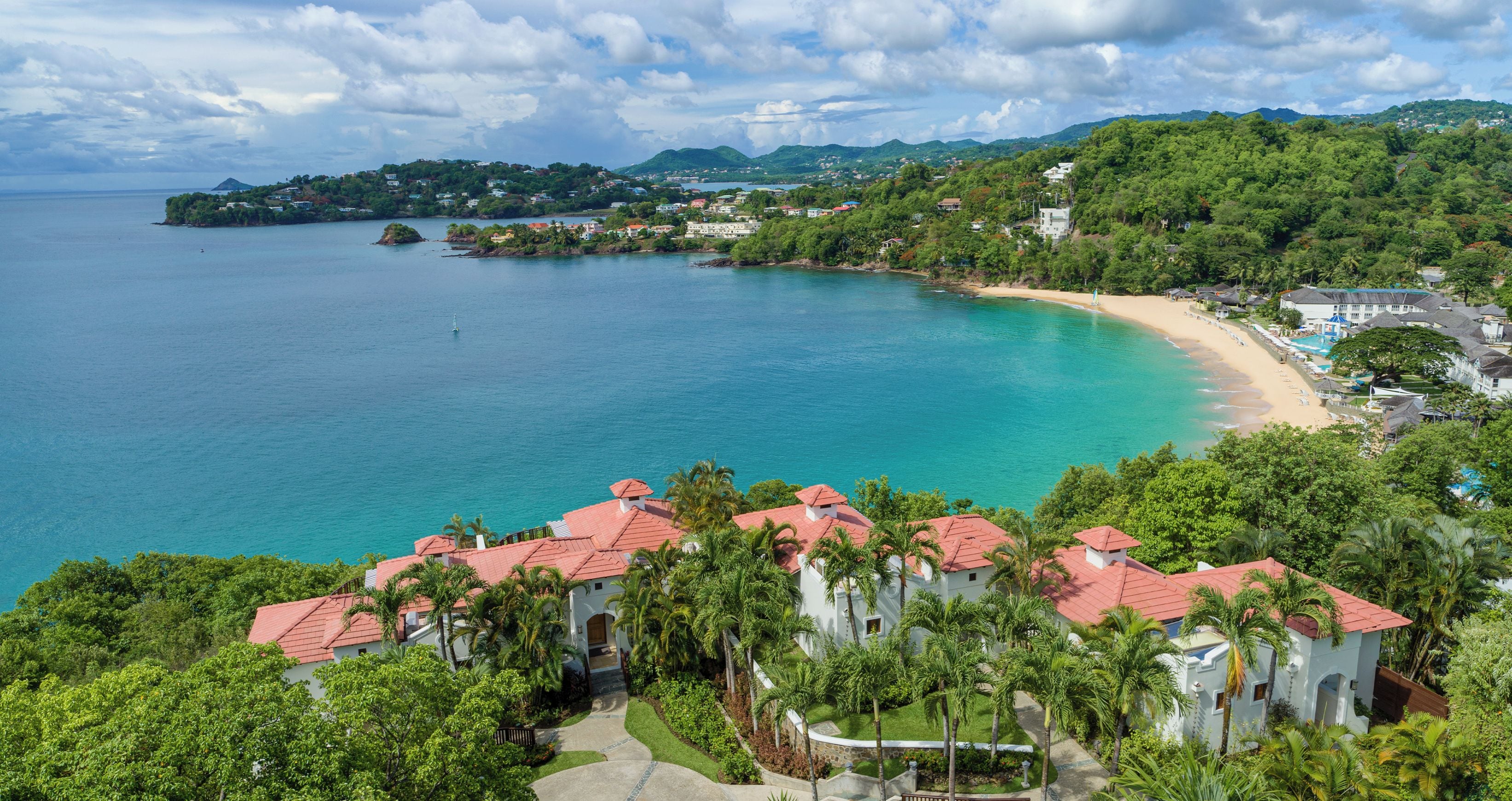 A coastal resort with a beach, clear waters, and lush greenery.
