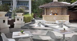 An outdoor patio with white wicker furniture, a stone fireplace, and potted plants. - Sandals Regency La Toc (Castries)