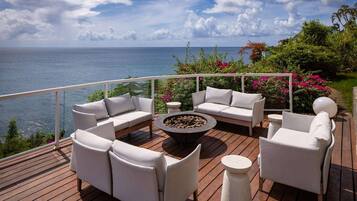 Una terraza con mobiliario exterior, un pozo de fuego y vistas al océano.