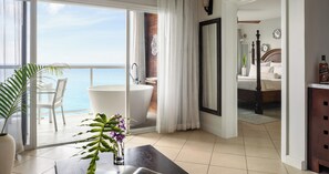 A hotel room with a balcony, a large bathtub, a bed, and a view of the sea. - Sandals Regency La Toc (Castries)