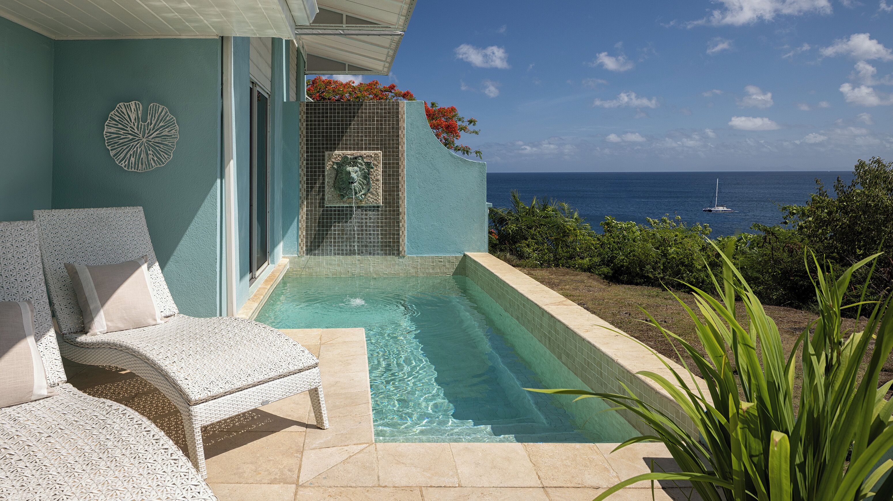 Zona de piscina con vista al océano, área de descanso techada y una pared decorativa.