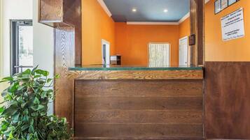 A reception area with a wooden counter, a potted plant, and a sign on the wall.