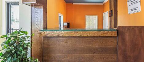 A reception area with a wooden counter, a potted plant, and a sign on the wall.